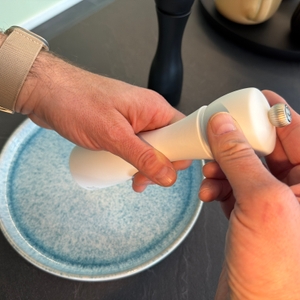 Eine Hand dreht an der Salzmühle vom Peugeot 2/24277 Tahiti Duo.