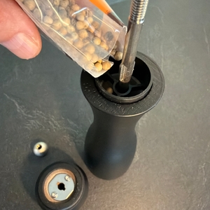 Pfefferkörner werden in die Pfeffermühle aus dem Peugeot 2/24277 Tahiti Duo gegeben.