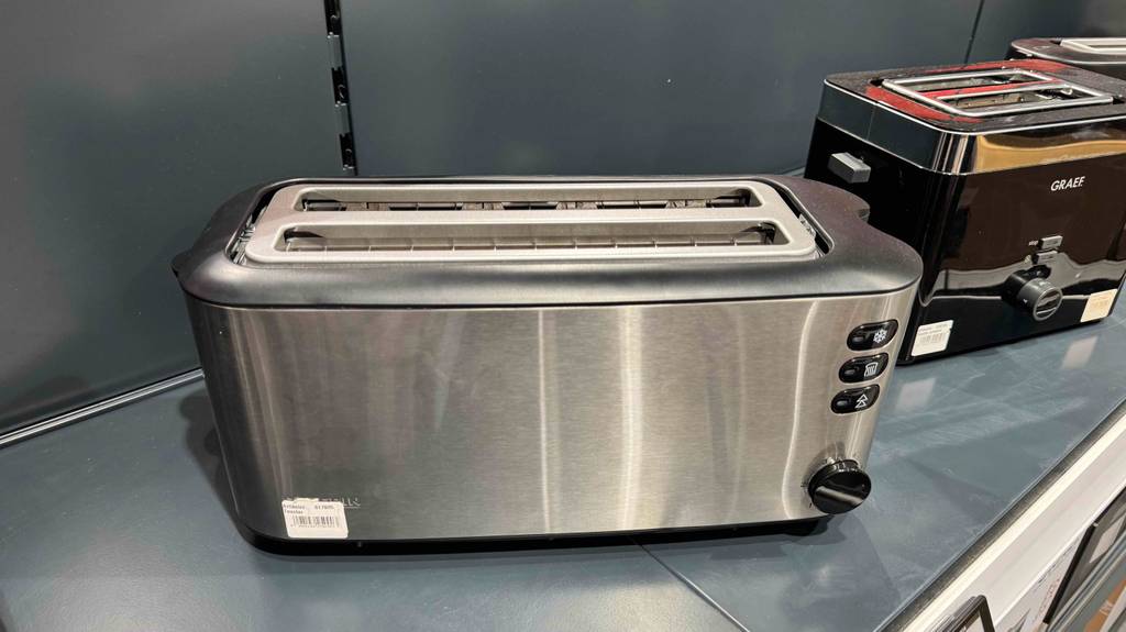 Im Test: Der Doppel-Langschlitztoaster aus Edelstahl, von oben betrachtet, steht auf einem grauen Regal neben weiteren Toastermodellen.