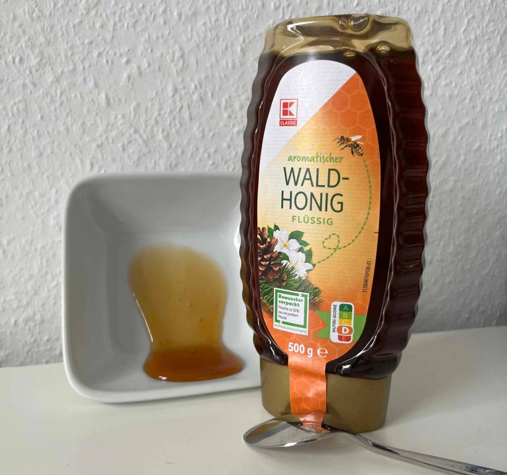 Waldhonig getestet: eine Flasche Waldhonig steht neben einer Schüssel mit Honig darin.