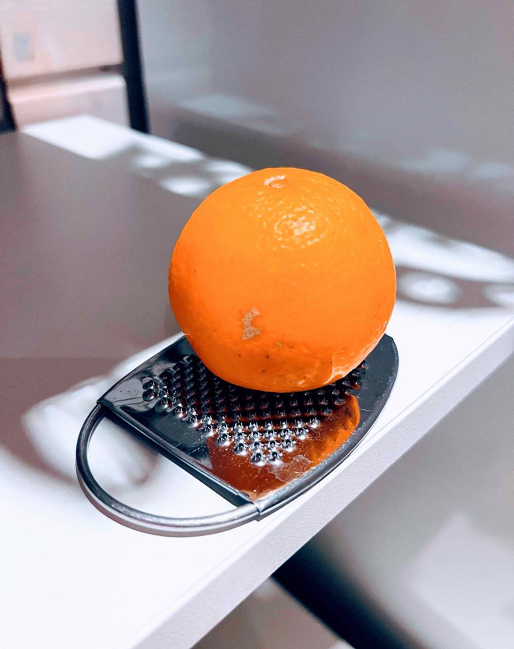 Zester-Reibe getestet: eine Orange liegend auf einer Zester-Reibe.