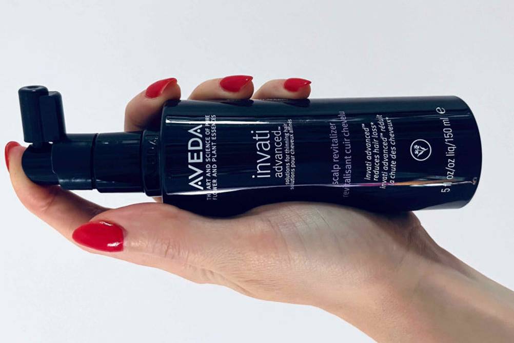 Haarwuchsmittel-Test: Haarwuchsmittel in der Hand vor einer weißen Wand.