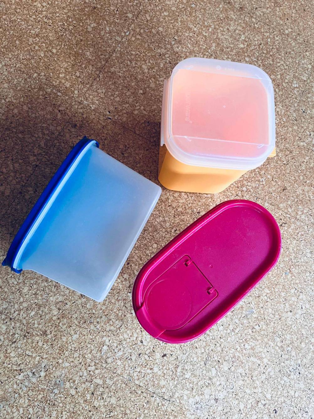 Tupperware getestet: Meherer Dosen in unterschiedlichen Farben liegen auf einer Holzoberfläche.