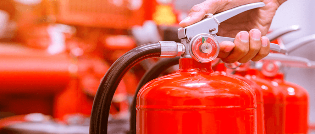 2-kg-Feuerlöscher im Test: Eine Hand auf dem Hebel eines Feuerlöschers