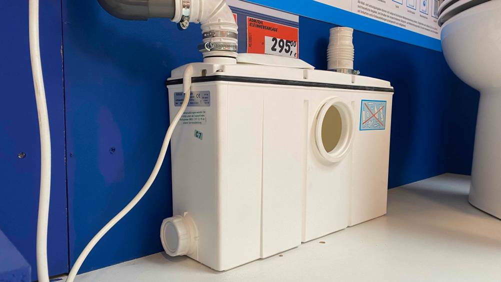Im Test: Eine Hebeanlage von schräg vorne vor einer blauen Wand auf einer hellen Fläche.