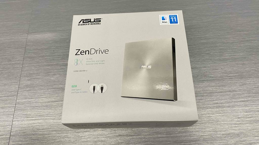 Auf einem grauen Boden liegt ein getesteter DVD-Brenner von asus.