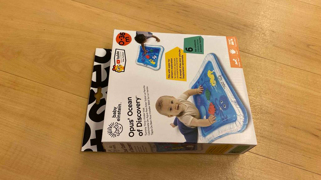 Wasserspielmatte getestet: Eine verpackte Wasserspielmatte liegt horizontal auf einer Holzfläche.
