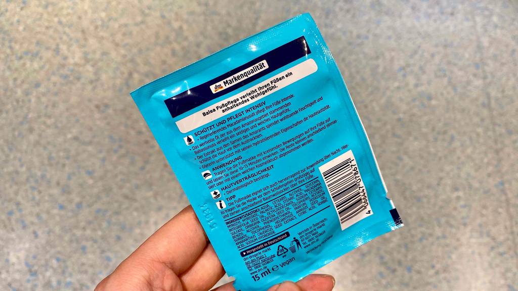 Verpackung von Fußmaske in der Hand - Rückseite mit Informationen.