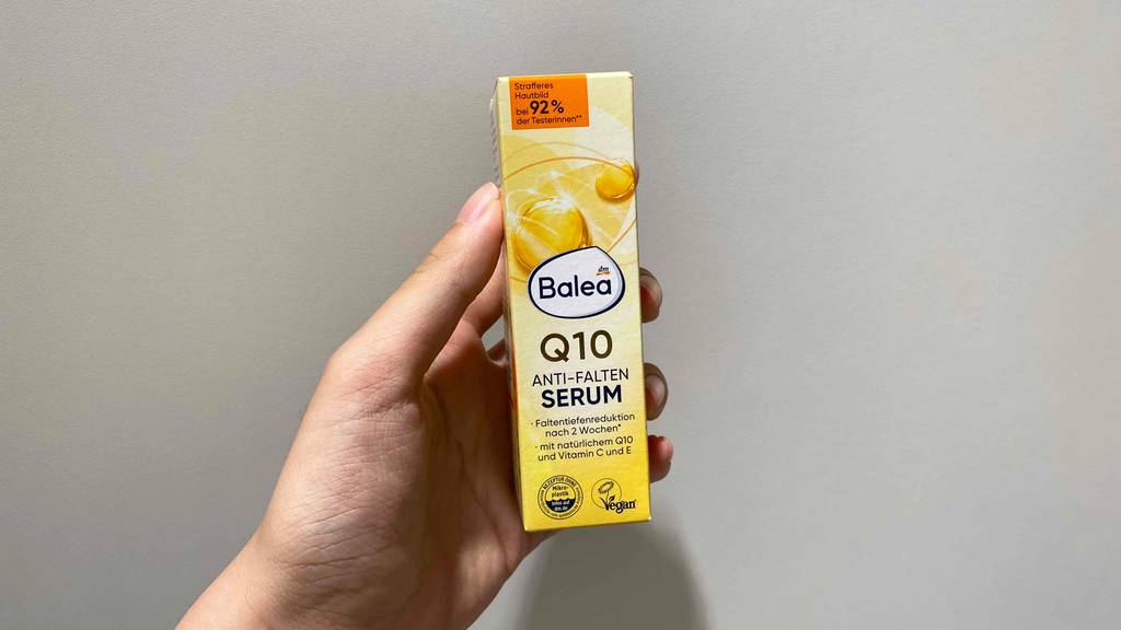 Anti-Falten-Serum im Test: Eine Hand hält eine Packung Serum vor grauen Hintergrund