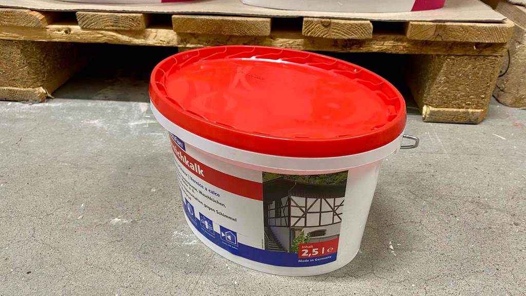 Kalkfarbe getestet: Vor einer Holzpalette steht ein Eimer Kalkfarbe.
