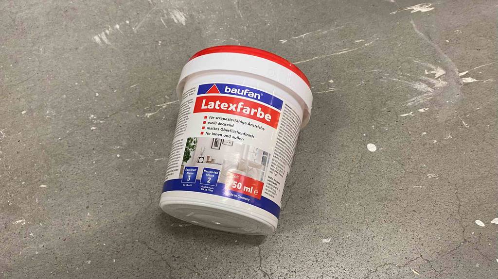 Latexfarbe getestet: Ein Eimer liegt auf einer grauen Fläche.