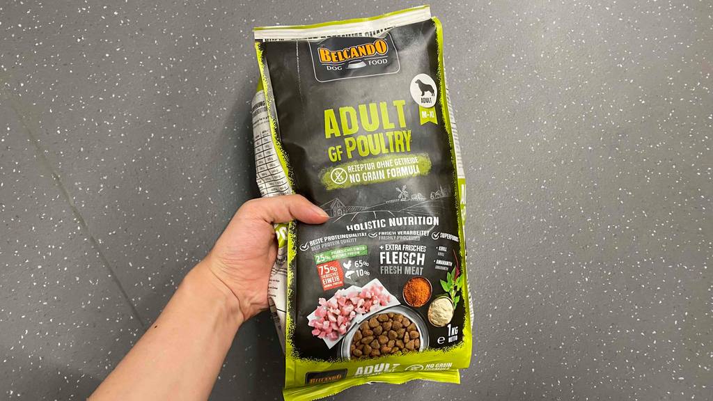 Belcando-Trockenfutter im Test: Verpackung des Belcando-Trockenfutters wird in der Hand über grauem Boden gehalten