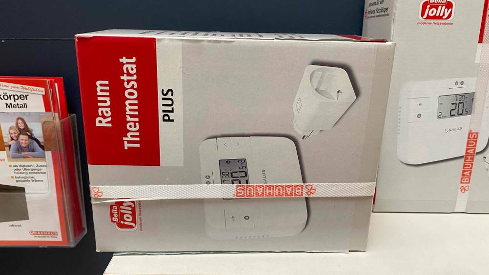 Ein gestestetes Raumthermostat in Originalverpackung liegt auf der Seite auf einer hellen Fläche.