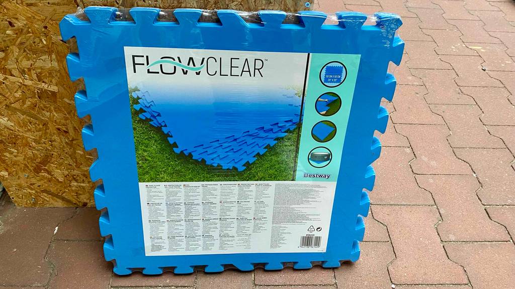 Bodenschutzmatte im Test: eine Bodenschutzmatte in Blau in einer Plastikverpackung im aufrecht angelehnten Zustand.