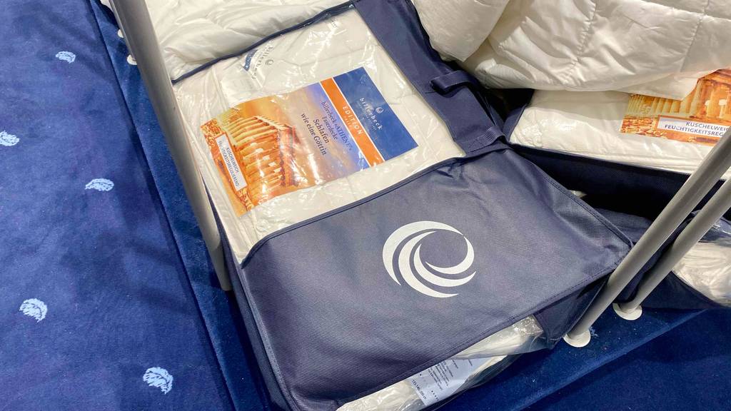 4-Jahreszeiten-Bettdecke getestet: Eine verpackte Decke auf einer blauen Fläche.