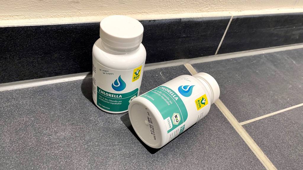Im Test: Zwei Dosen Chlorella auf einem grauen Boden, eine stehend, eine liegend