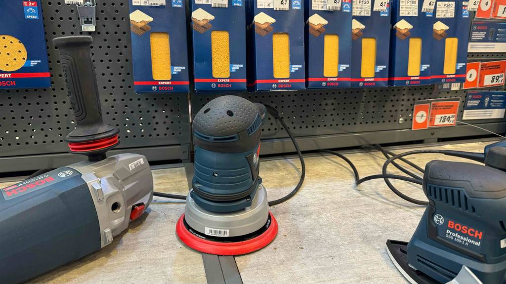 Der getestete 150-mm-Exzenterschleifer steht in einem Regal neben anderen Geräten.