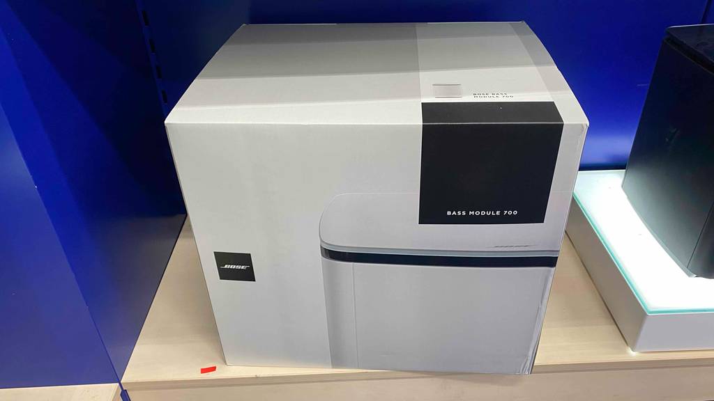Subwoofer getestet: Ein verpacktes Gerät in einem Regalfach von vorne.