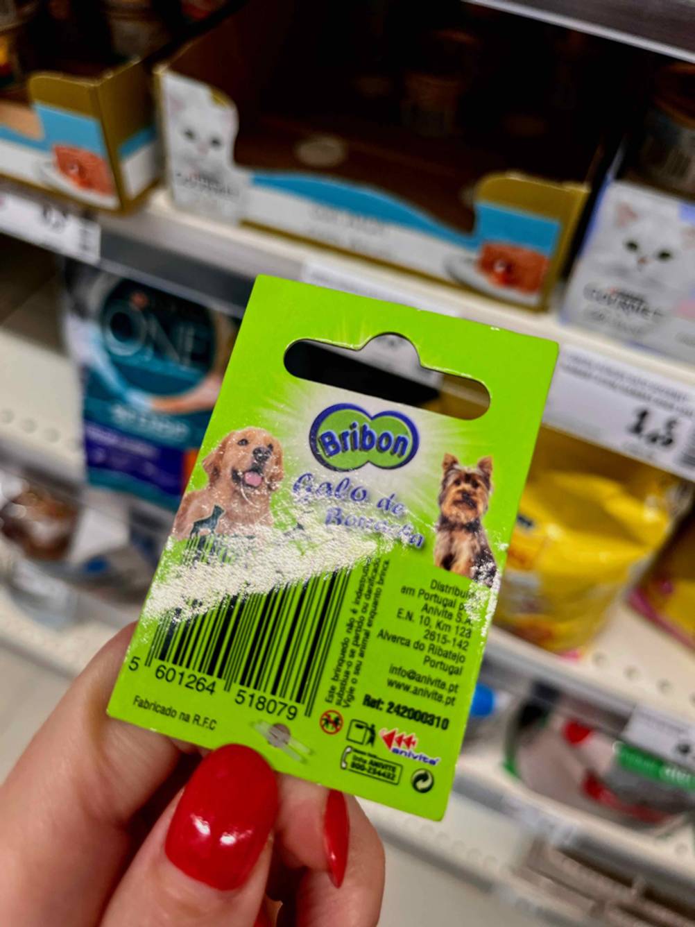 Hundespielzeug getestet: Eine Hand hält einen bedruckten Karton mit Logo hoch, im Hintergrund ein Regal