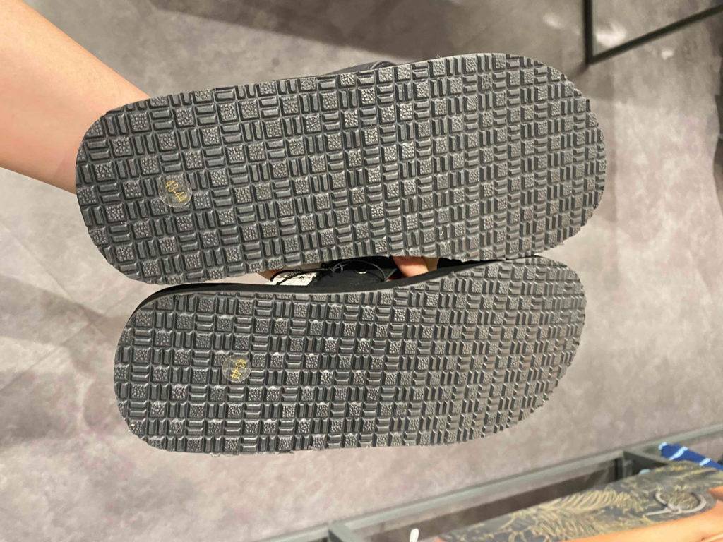 Flip-Flops-Herren-Test: ein Paar Flip-Flops werden in der Hand gehalten, mit Blick auf die Sohlen.