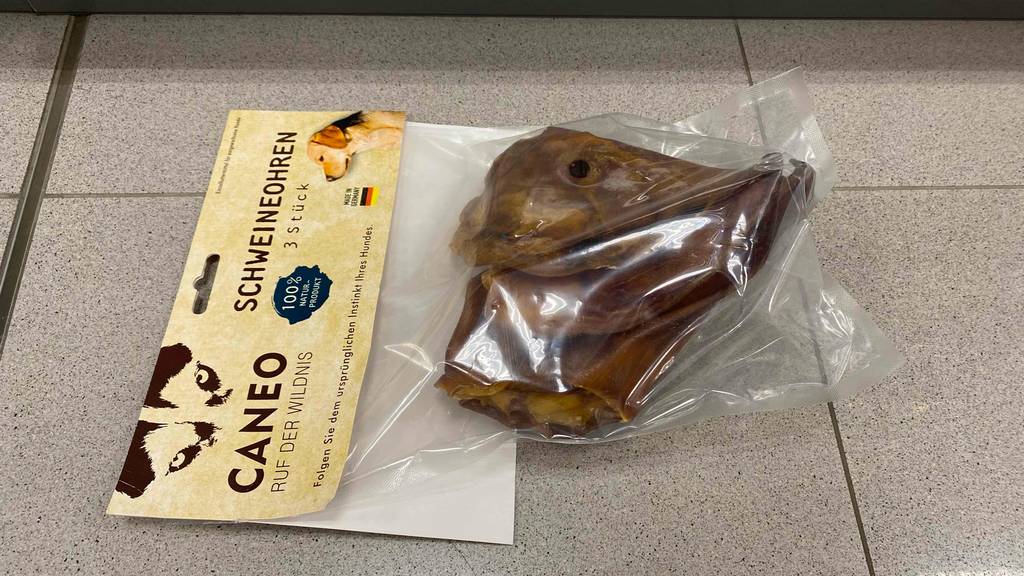 Schweineohren-Hund-Test: Auf einem Fliesenboden liegt eine Packung mit Schweineohren für Hunde.