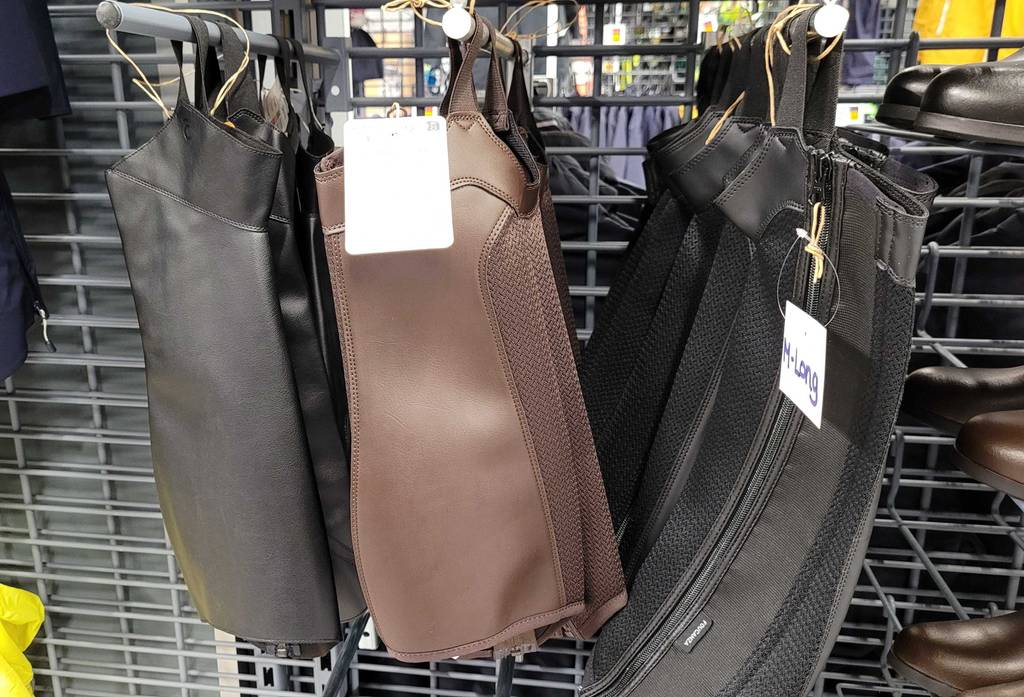 Mehrere getestete Reitchaps hängen in einem Regal.