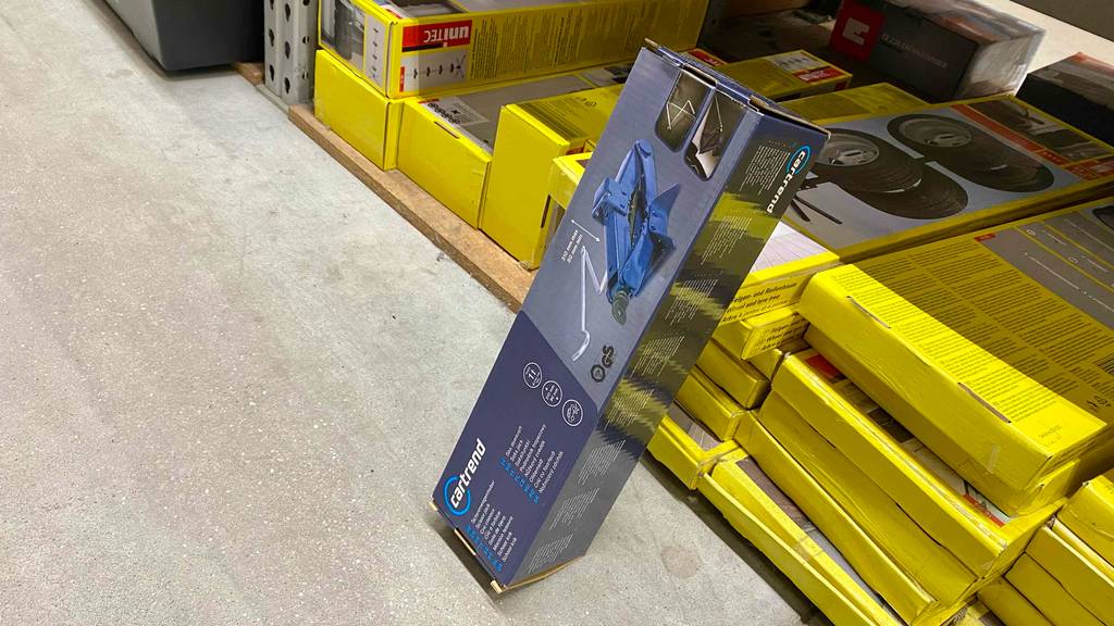 Scherenwagenheber getestet: Ein verpacktes Gerät lehnt an einem Regal.
