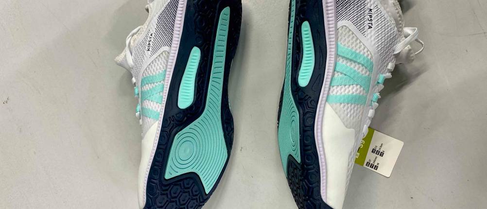 Volleyballschuhe für Damen-Test: Nahaufnahme der schwarz-türkisfarbenen Schuhsohlen, beide Schuhe liegen auf der Seite auf einem weißen Boden.