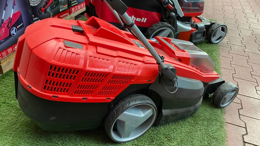 Einhell-Rasenmäher im Test: roter Einhell-Rasenmäher vor Verpackungen des Rasenmähers.