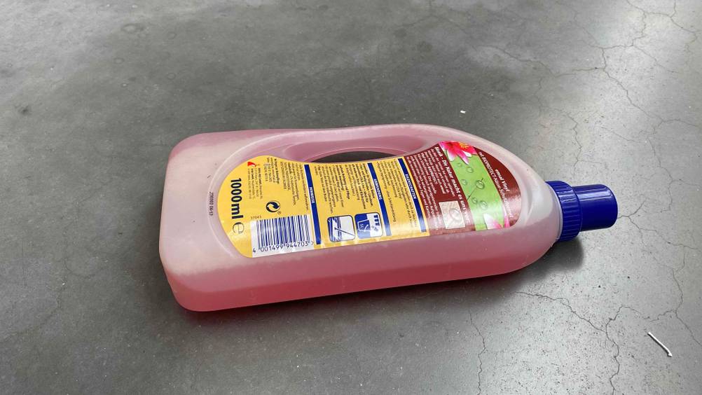 Im Test: Eine Flasche Vinylboden Pflege liegt mit ihrer Rückseite nach oben auf einer grauen Fläche
