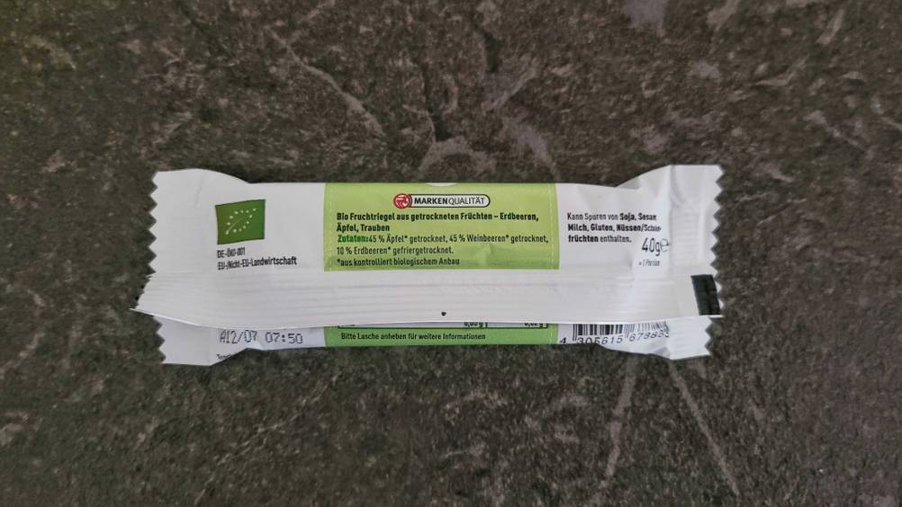 Die Rückseite der Verpackung eines getesteten Fruchtriegels auf dunklem Hintergrund.