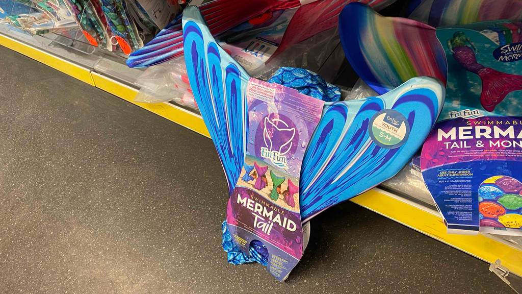 Eine getestete Meerjungfrauen-Flosse für Kinder lehnt an einem Regal.
