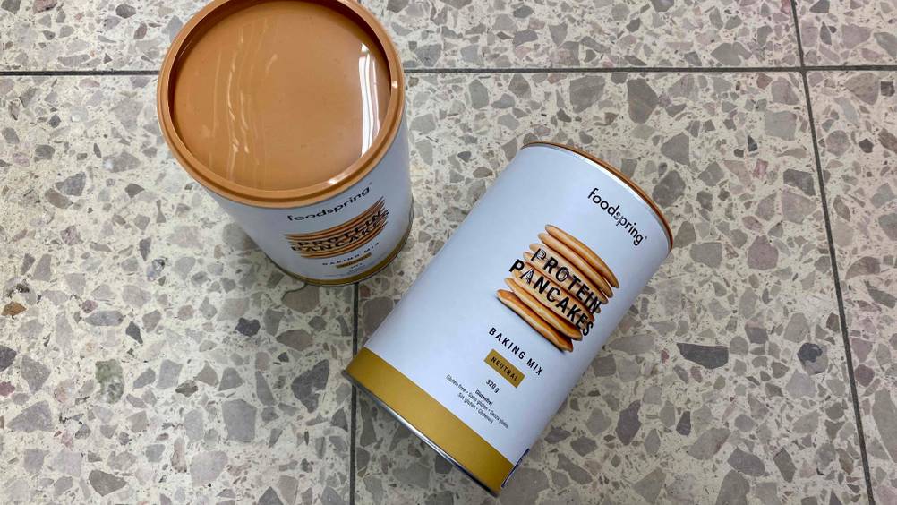 Protein Pancake im Test: Zwei Dosen Protein Pancake eine stehend eine liegend auf einem Fließenboden
