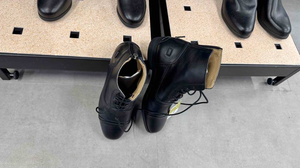Die Lederreitstiefel, welche getestet wurden lehnen an einem Regal.