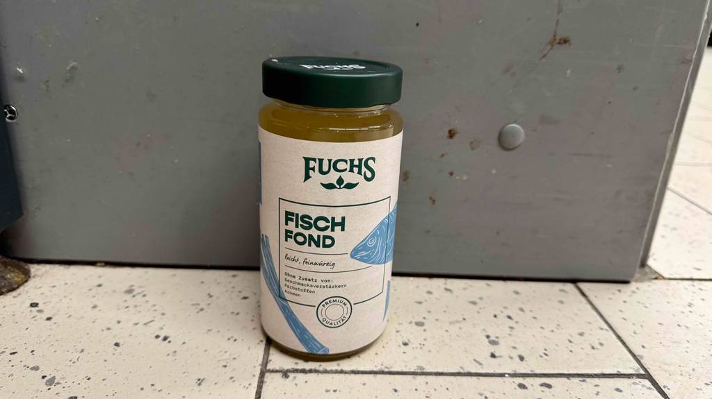 Test: Ein Glas Fischfond von Fuchs steht vor einer Wand.