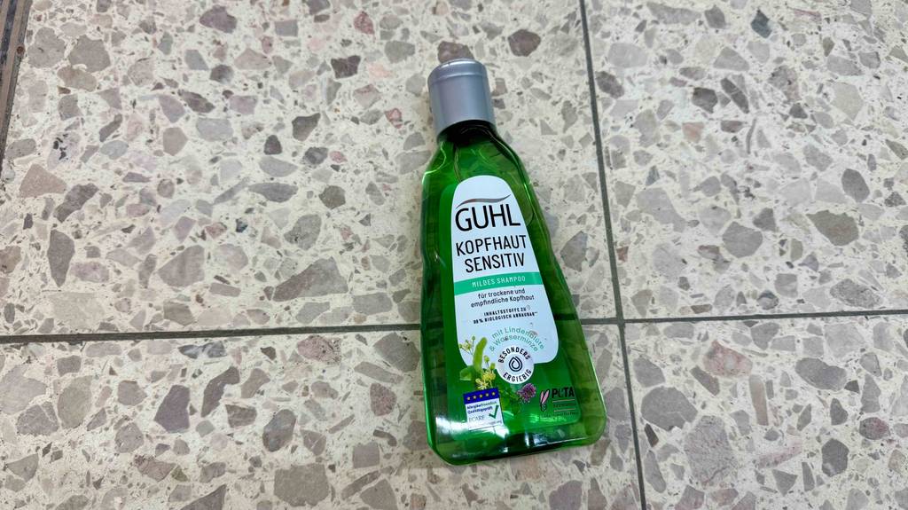 Eine Flasche des getesteten milden Shampoos der Marke Guhl, das auf einen Boden platziert wurde.