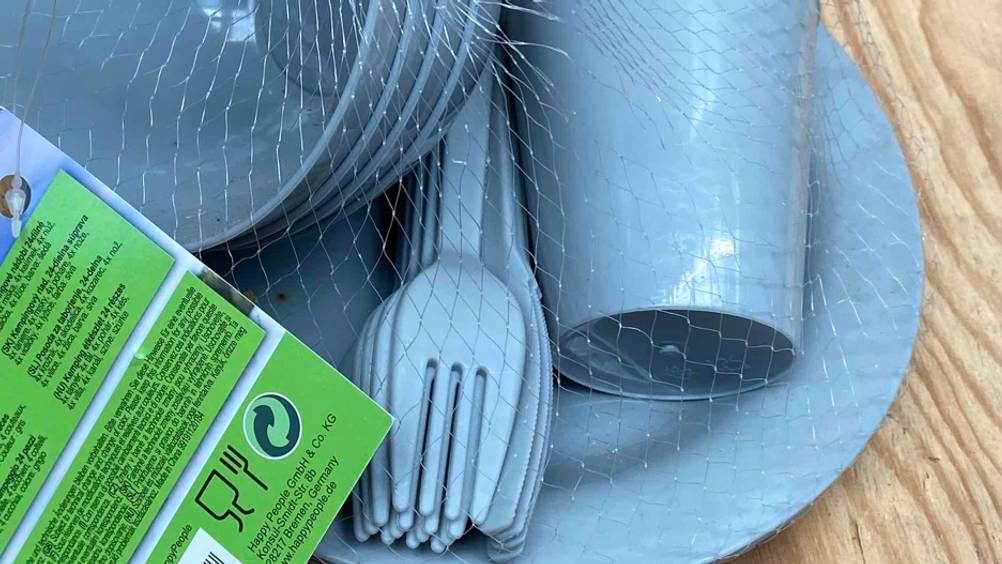 Campinggeschirr getestet: Campinggeschirr in einem Netz mit Fokus auf Besteck.