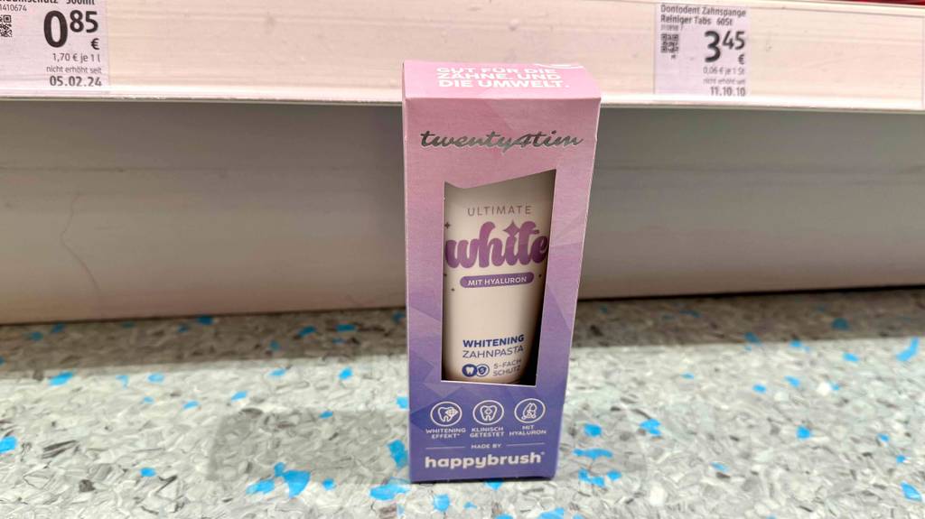 Eine Packung getestete Whitening-Zahnpasta steht vor einem Regal.