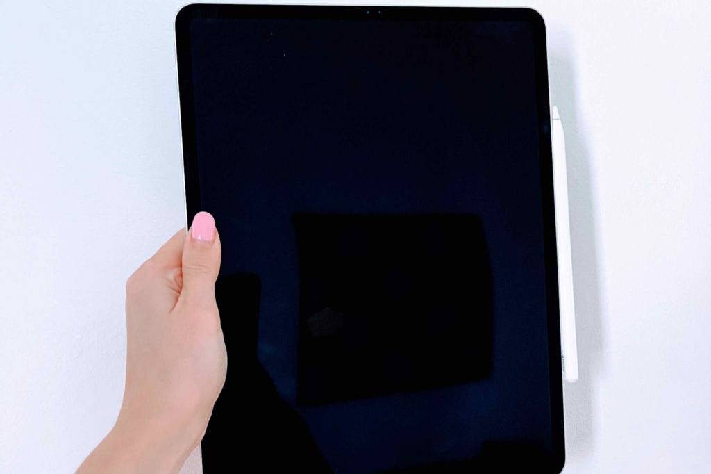 Tablet mit Stift im Test: Hand hält ein Tablet mit Stift gegen eine helle Wand