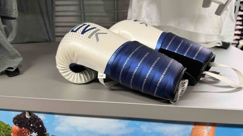 Die getesteten Boxhandschuhe in 10 oz liegen in einem Regal, während die Seiten im Fokus stehen.