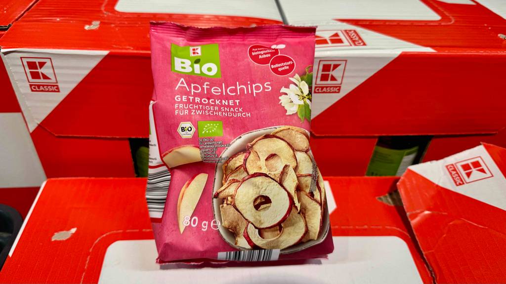 Getestete Apfelchips in verschlossener Packung sind auf roten Kartons platziert.