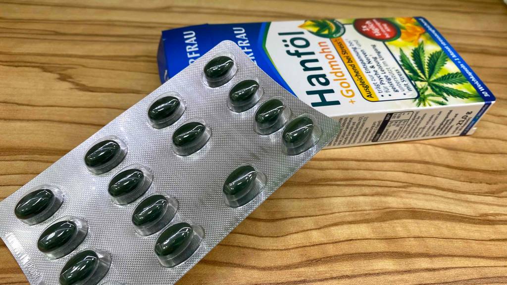 Hanföl-Kapseln liegen neben der Verpackung auf einem Tisch