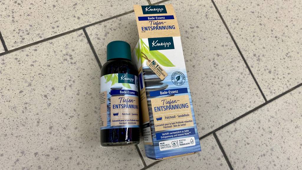 Badeöl getestet: Eine Flasche Öl liegt neben ihrer Verpackung auf einem Fließenboden