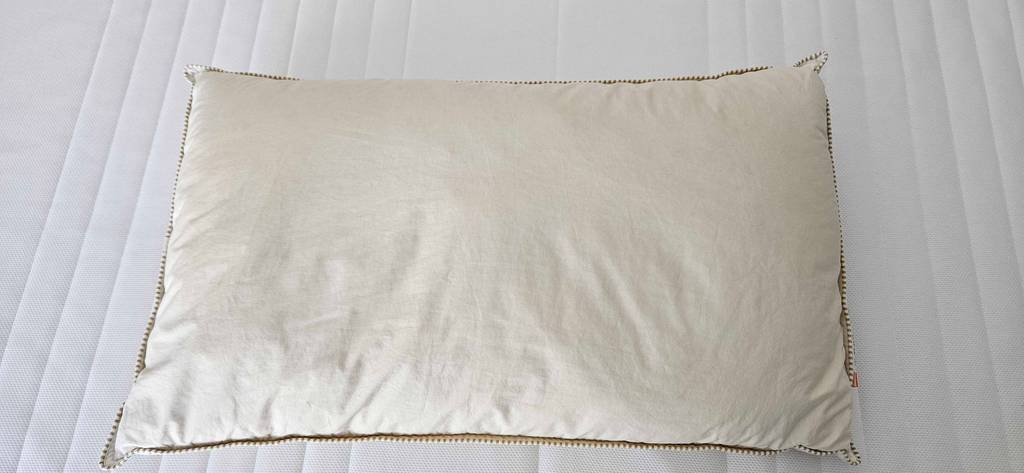 Ein Kopfkissen mit Maßen von 40 x 60 cm liegt auf einem Bett.