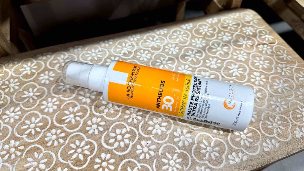 Im Test: Eine La-Roche-Posay-Sonnencreme in der Sprühflasche aus Kunststoff liegt auf einer gemusterten Holzkiste.