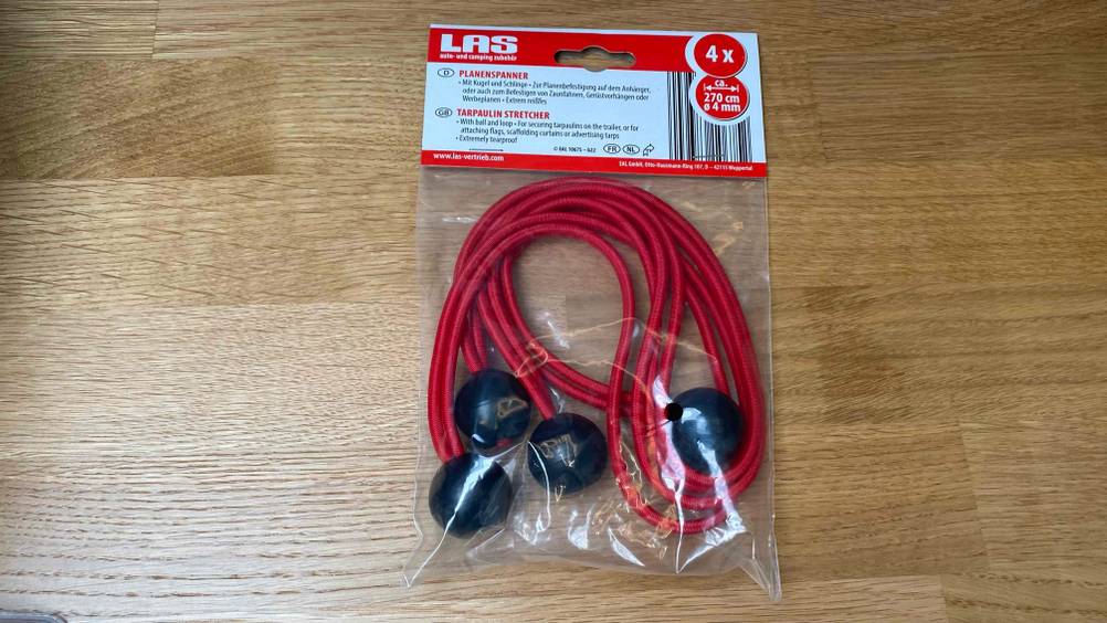 Expander getestet: Ein roter Expander in seiner Verpackung von oben auf einem Holzboden.