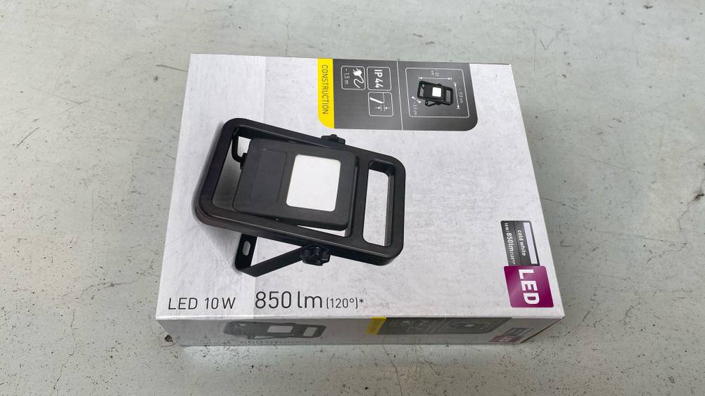 LED-Baustrahler getestet: Ein verpackter LED-Baustrahler von schräg oben auf einer hellen Oberfläche.