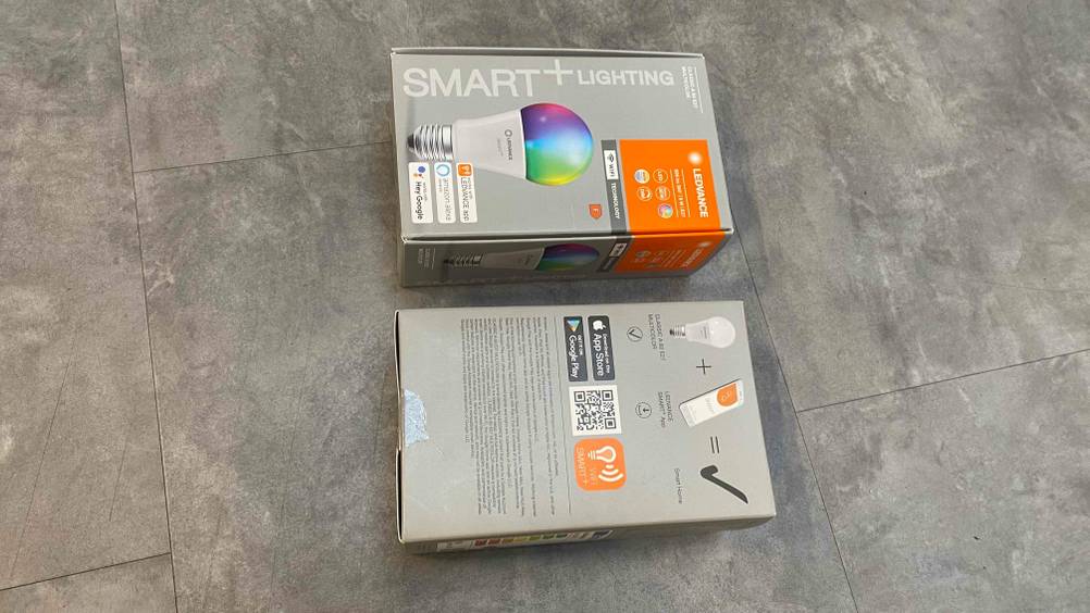  Smart-Glühbirne im Test: eine Verpackung einer Smart-Glühbirne im liegenden Zustand von der Rückseite ersichtlich und eine von vorn.