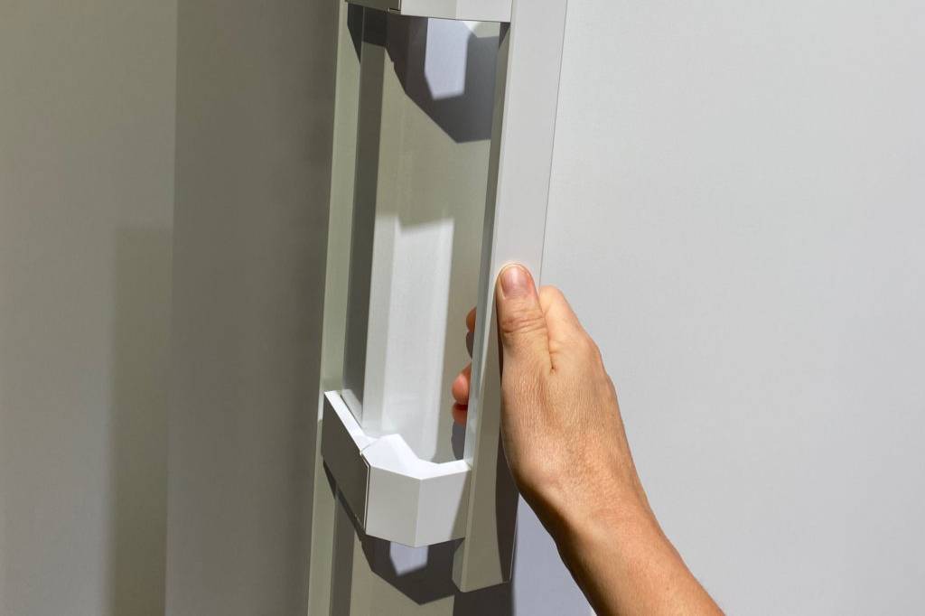 Getesteter Kühlschrank mit Gefrierfach mit Hand an Griff