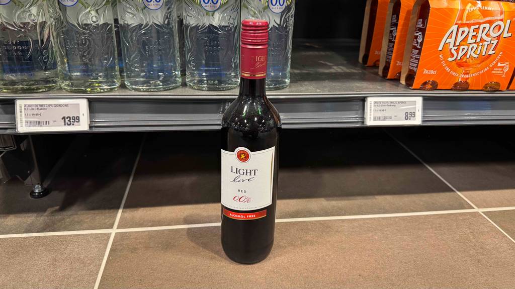 Eine Flasche getesteter alkoholfreier Rotwein steht vor einem Regal mit anderen alkoholischen Getränken.